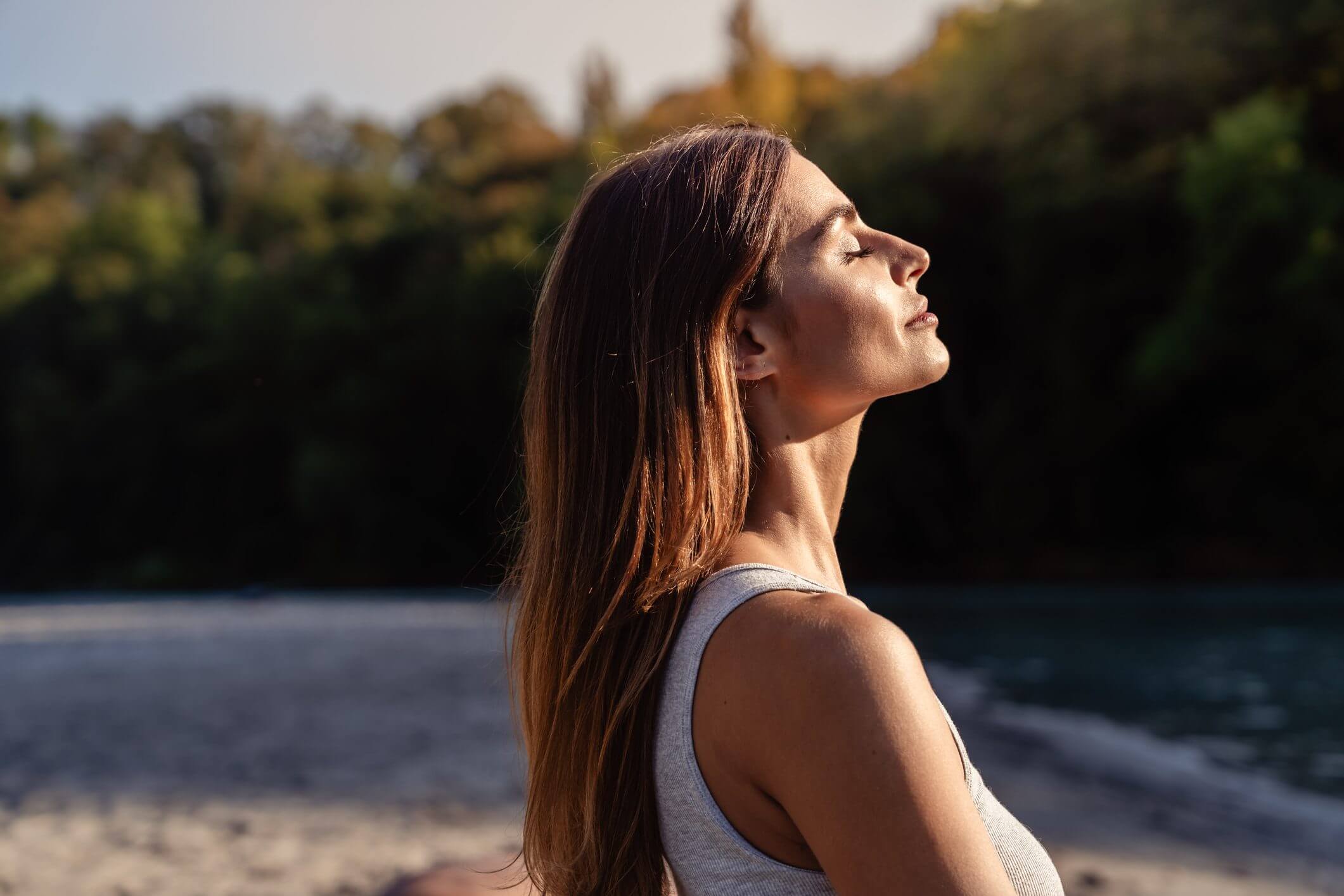 Woman enjoying sunlight with eyes closed outdoors.